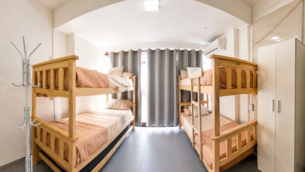 Een kamer met stapelbedden, een kapstok, een kledingkast en een raam met gordijnen.