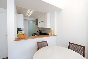 Eine moderne Küche mit weißen Schränken, einer Holz Arbeitsplatte und einem Essbereich mit Tisch und Stühlen.