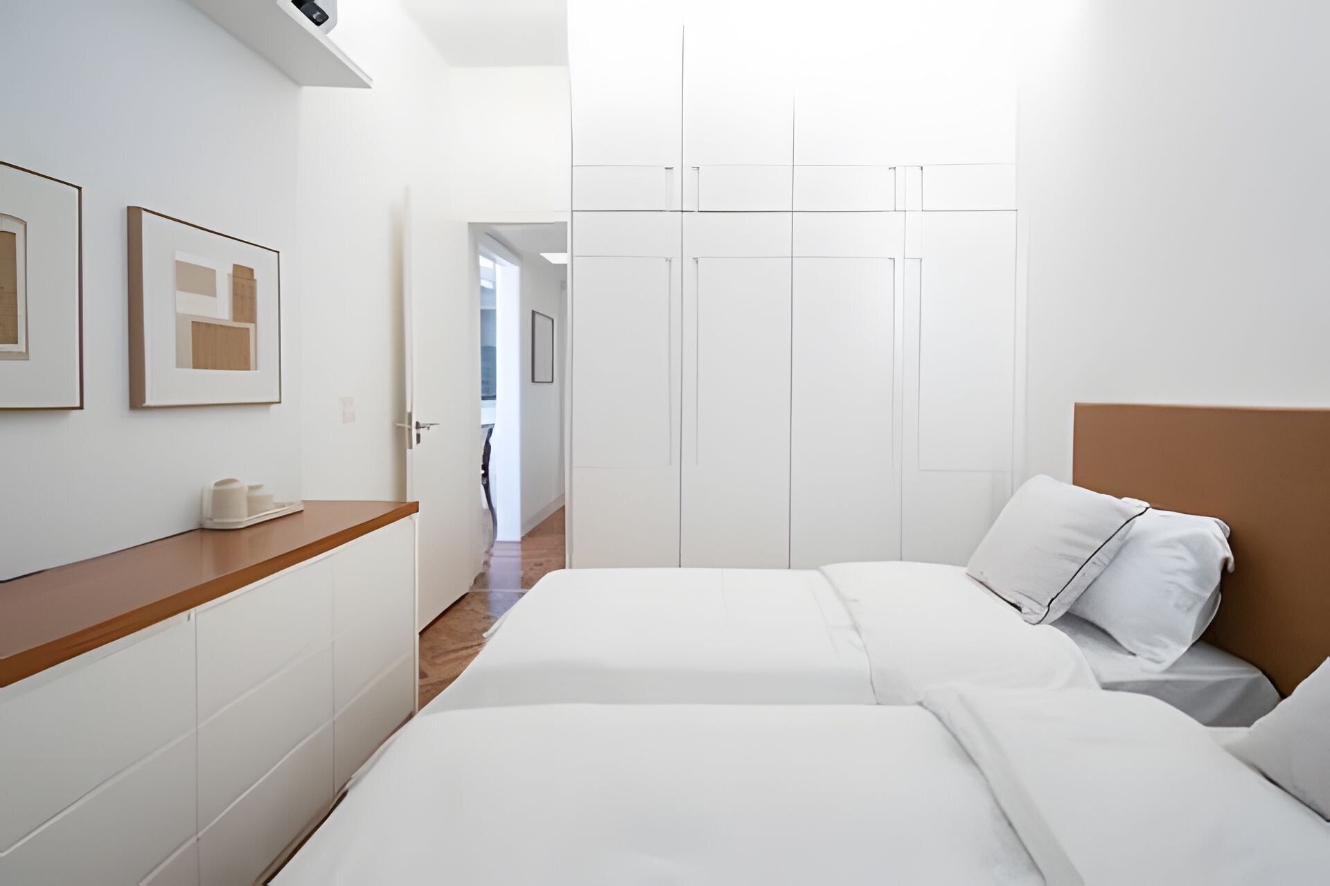 Una habitación de hotel con dos camas, un aparador de madera y un armario.