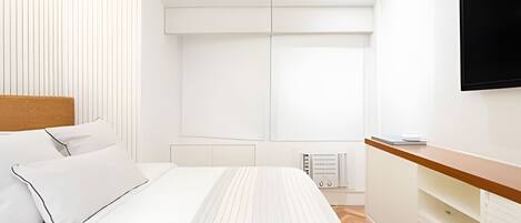 A modern bedroom with a bed, a TV, a bedside table, and a radiator.