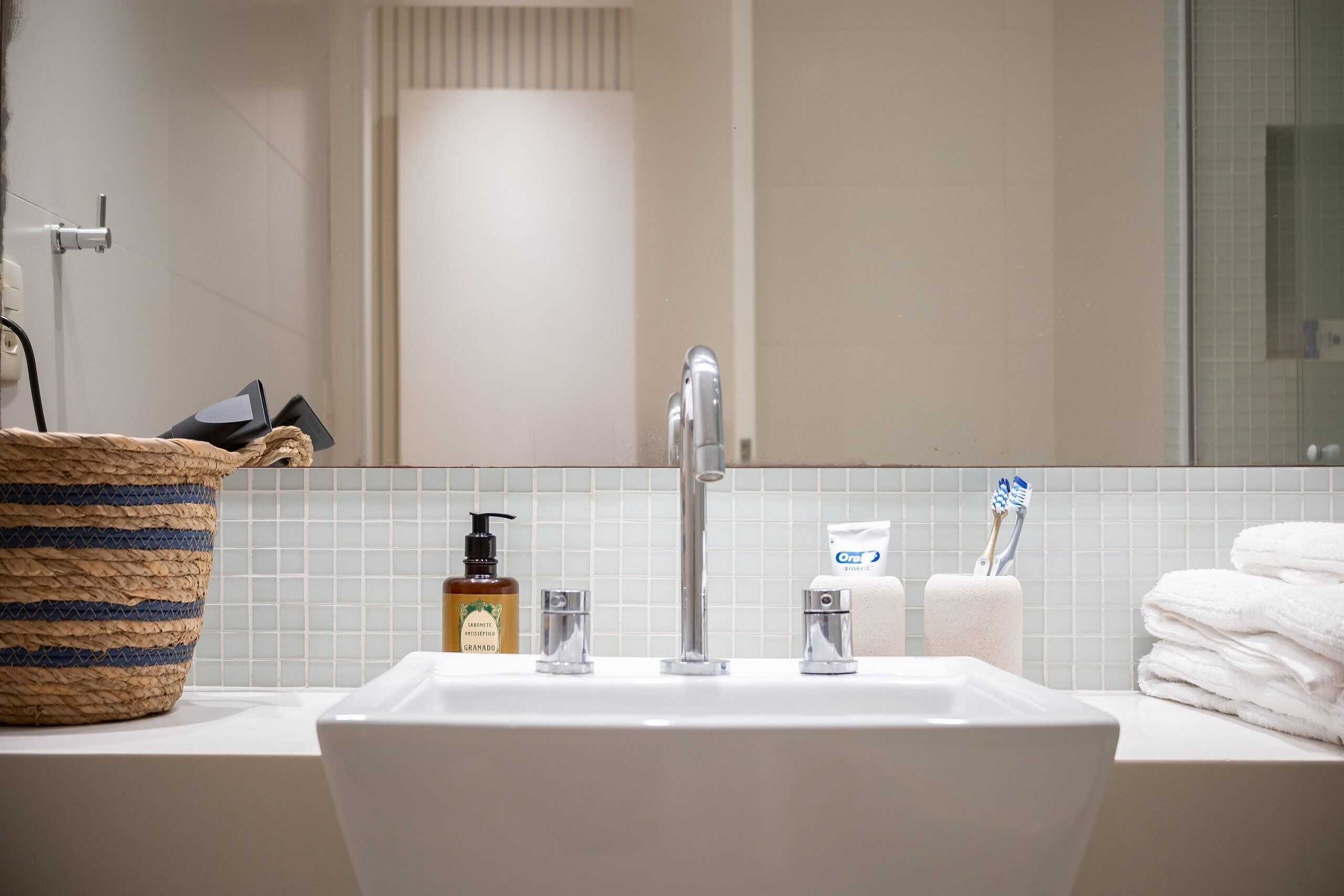 Une salle de bain équipée d’un lavabo, d’un miroir, d’articles de toilette et de serviettes.