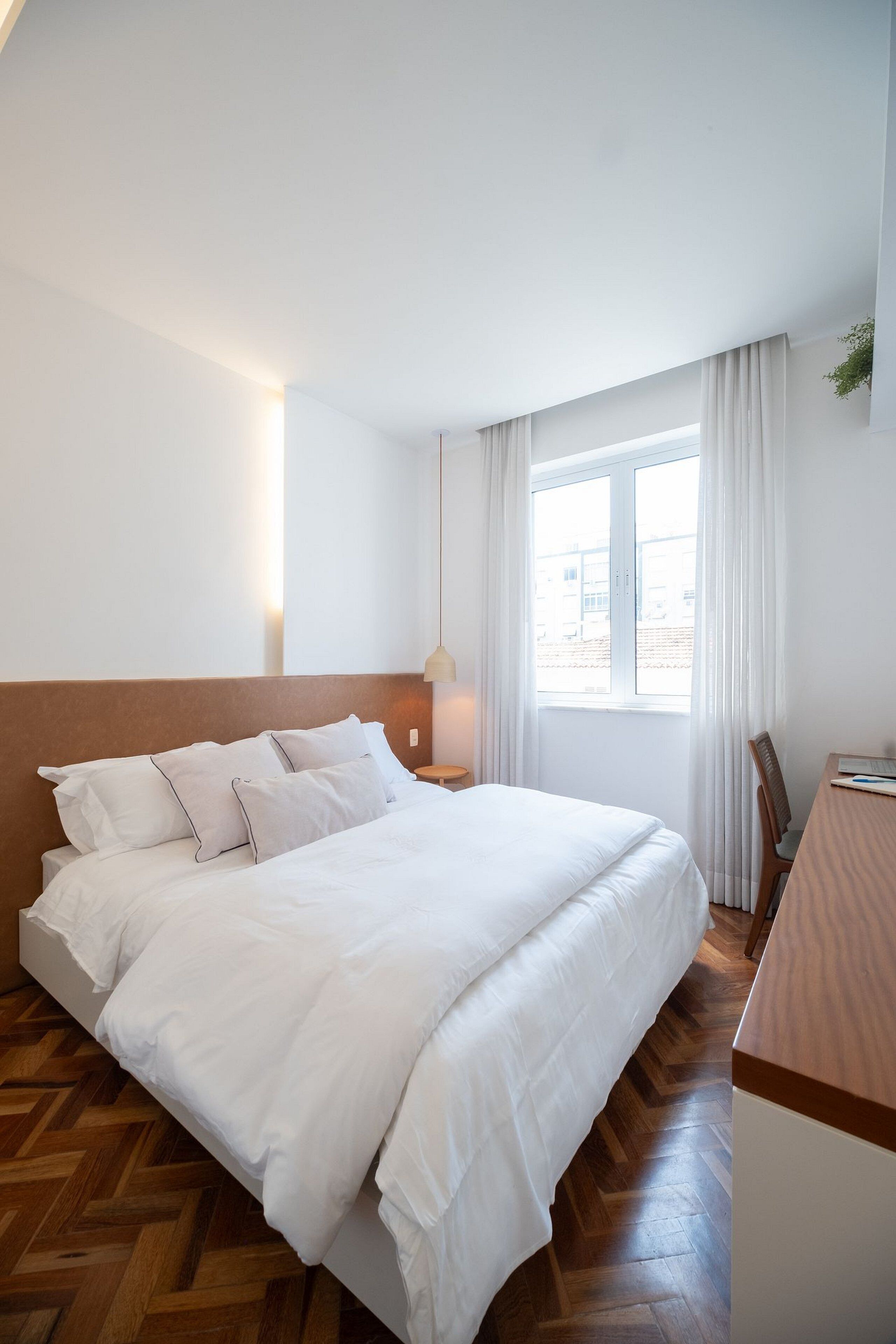 Une chambre d’hôtel avec un grand lit, un bureau et une fenêtre avec des rideaux.