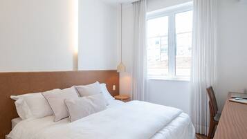 Une chambre d’hôtel avec un grand lit, un bureau et une fenêtre avec des rideaux.