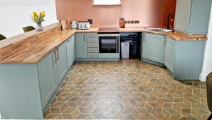 A compact kitchen with a window, a dishwasher, and a microwave. - Apartment Sleeps 4 With Balcony and Parking (Kingsbridge)