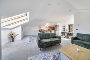 A spacious living area with a high ceiling, a skylight, and a modern kitchen in the background.