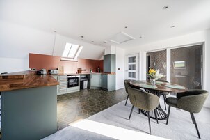 Una cocina moderna con una isla central, un comedor con sillas y un amplio ventanal con vistas.
