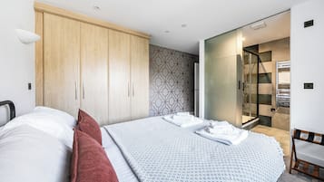 Et moderne soveværelse med seng, garderobeskab, bruseområde og væg med mønster.