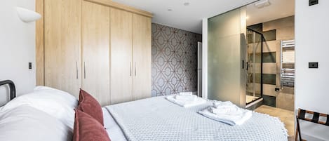 Un dormitorio moderno con cama, armario, zona de ducha y pared con estampado.