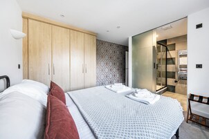 A modern bedroom with a bed, a wardrobe, a shower area, and a patterned wall.