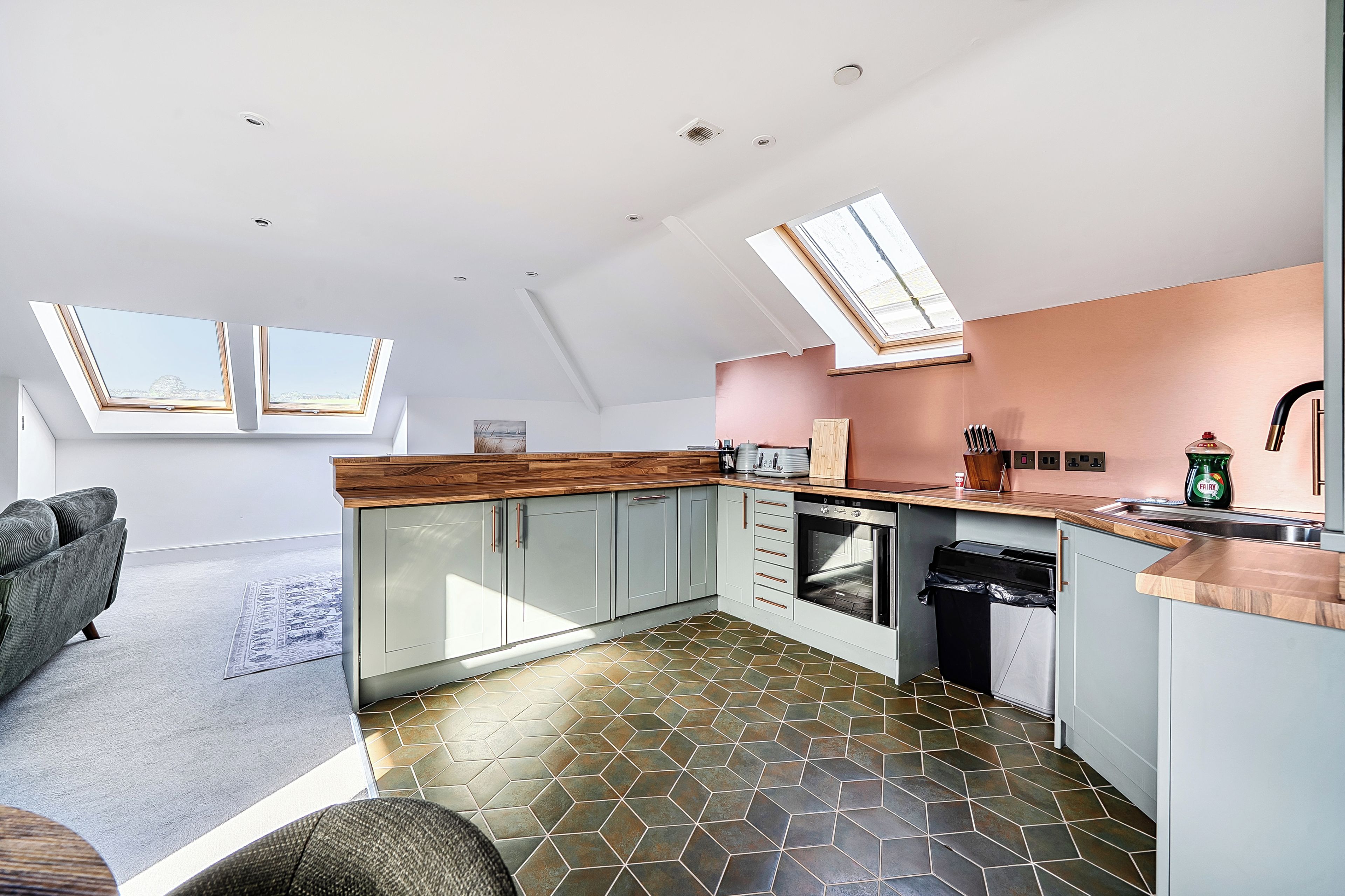 A modern kitchen with skylights, a dining area with a sofa, and a patterned floor.