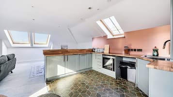 Et moderne køkken med ovenlys, et spiseområde med en sofa og et mønstret gulv.