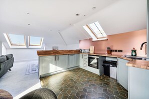 A modern kitchen with skylights, a dining area with a sofa, and a patterned floor. - Apartment Sleeps 4 With Balcony and Parking (Kingsbridge)