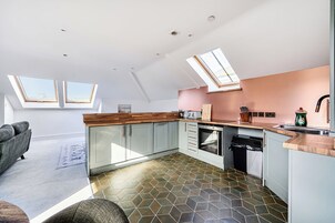 A modern kitchen with skylights, a dining area with a sofa, and a patterned floor.