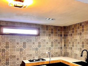 Une cuisine moderne dotée d’une cuisinière à gaz intégrée, d’un plan de travail en bois et d’un crédence décorée.