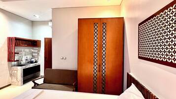 A hotel room with a bed, a sofa, a minibar, and a wardrobe.