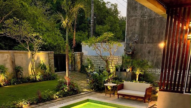 A swimming pool with a wooden deck, a bench, and a sofa. - Diafragma Livin (Nusa Dua)