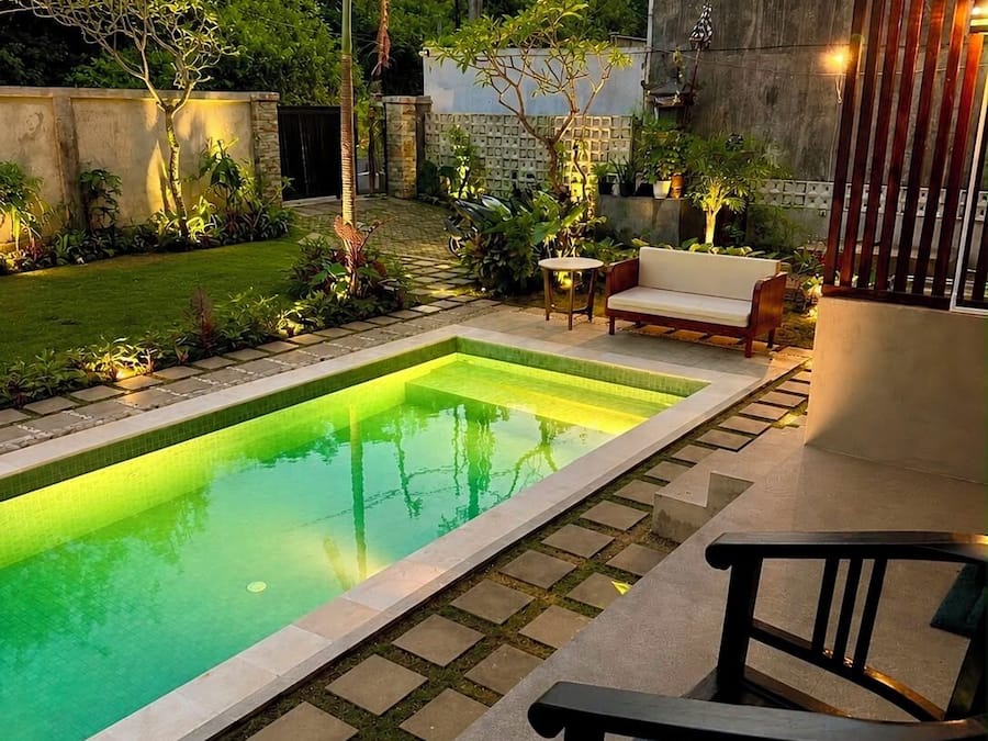 A swimming pool with a wooden deck, a bench, and a sofa.