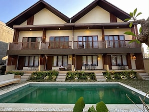 Un bâtiment à deux étages avec une piscine devant.