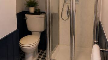 Ein Badezimmer mit einer Duschkabine, einer Toilette und einem Fußboden mit Muster.
