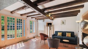 A room with a wooden ceiling, a blue sofa, a grey armchair, and a floor lamp. - Le Tsilaosa – Charm and Relaxation in the Heart of Périgord (Prigonrieux)