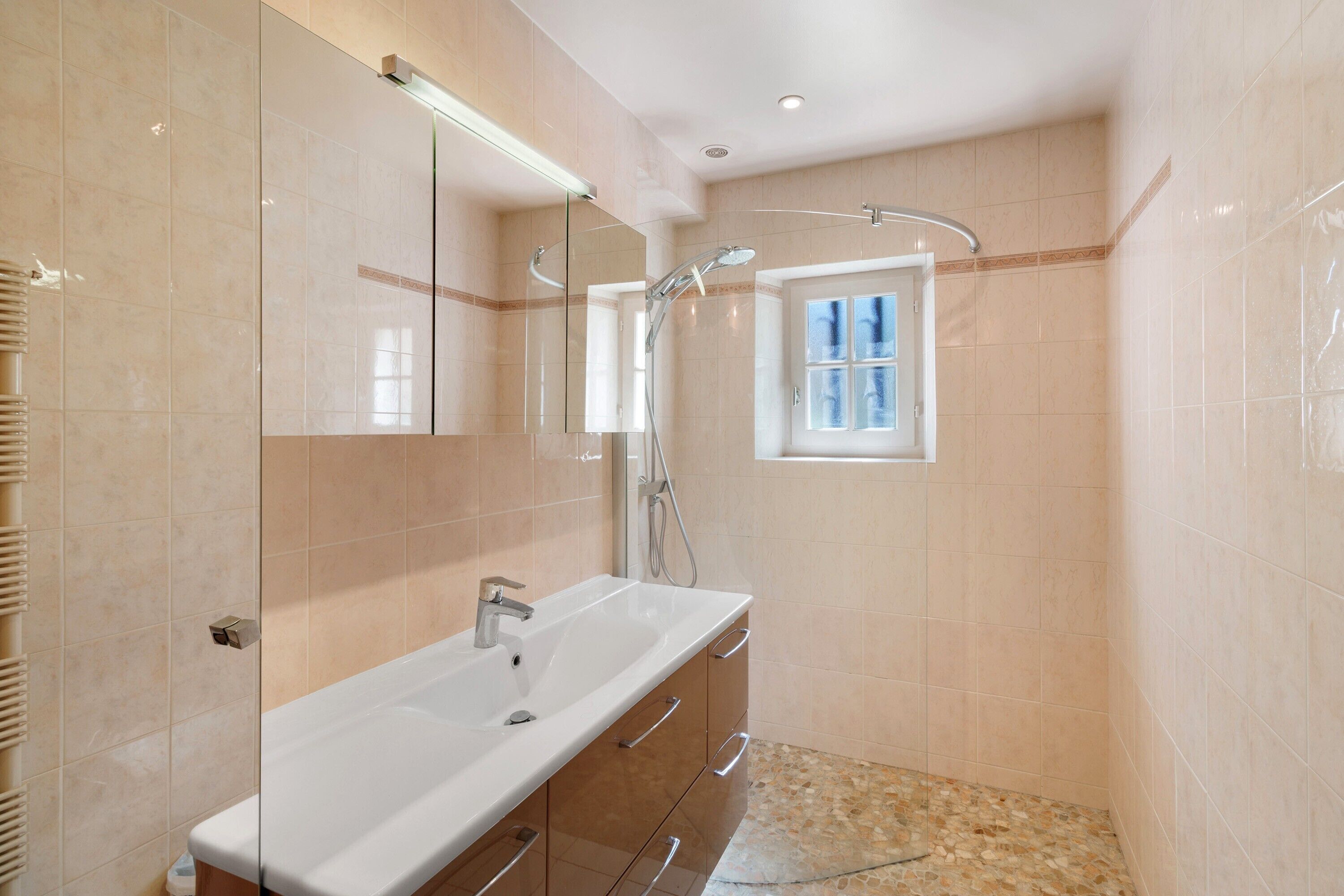 A bathroom with a large mirror, a sink, and a shower.