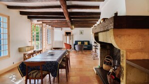A dining area with a long table, chairs, and a fireplace. - Le Tsilaosa – Charm and Relaxation in the Heart of Périgord (Prigonrieux)