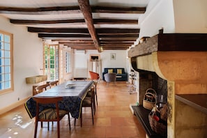 Un comedor con una mesa larga, sillas, chimenea y vistas al exterior.