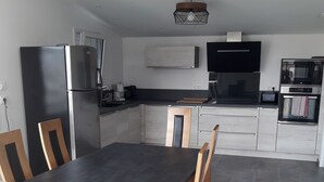 Ett modernt kök med ett matbord, stolar, ett kylskåp, en mikrovågsugn och en ugn.