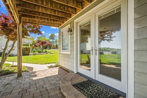 Ein überdachter Balkon mit Holzboden, eine Glastür mit Griff und eine Fußmatte.