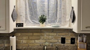 A kitchen with a double sink, a coffee bar sign, and a decorative plant.