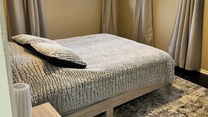 A bedroom with a bed, curtains, a window, and a rug.