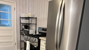 A kitchen with a stainless steel refrigerator, a stove, and a microwave.