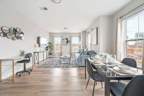 Ein modernes Wohnzimmer mit Essbereich, großen Fenstern und Blick auf die Stadt.
