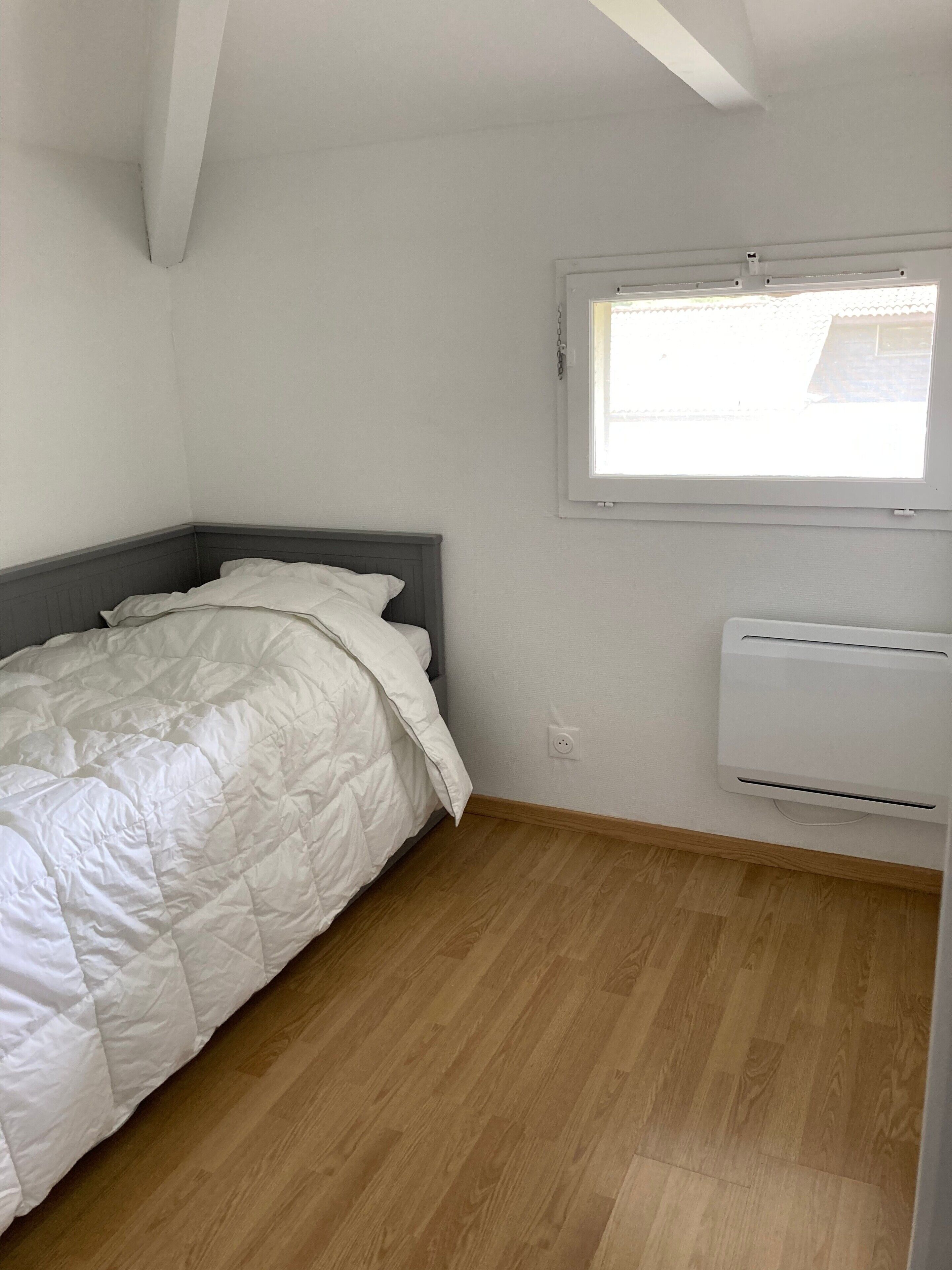 A bedroom with a bed, a window, and an air conditioning unit.