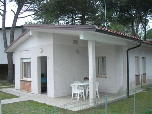 Ein eingeschossiges Gebäude mit überdachter Terrasse, einer Tür und einem Fenster.