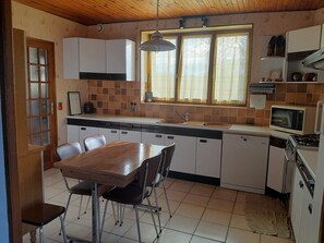 Eine kleine Küche mit Esstisch, Stühlen, einer Mikrowelle und Schränken.