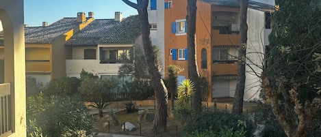 Un patio con un sendero adoquinado, rodeado de árboles y arbustos, que conduce a un edificio con techo de tejas y múltiples ventanas.