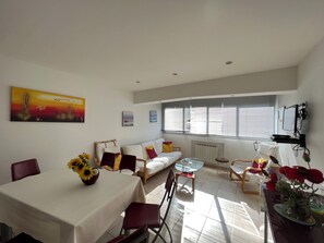 Una sala de estar moderna con comedor, que incluye un sofá, sillas, una mesa y obras de arte en las paredes.