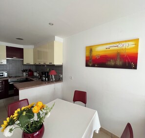 Una cocina moderna con comedor, un cuadro en la pared y una mesa con un jarrón de flores.