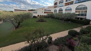 A multi-story building with balconies, a courtyard with trees, and a clear sky. - Terrasses du Lac – vue lac piscine clim parking terrasse (Le Grau-du-Roi)