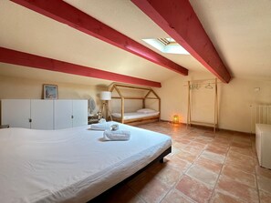 Ein Schlafzimmer mit einem großen Bett, einem Holzhochbett, einem Kleiderschrank, einem Schreibtisch mit Lampe und einer Heizung.
