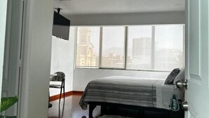 Quarto com cama, cadeira, janela e porta.