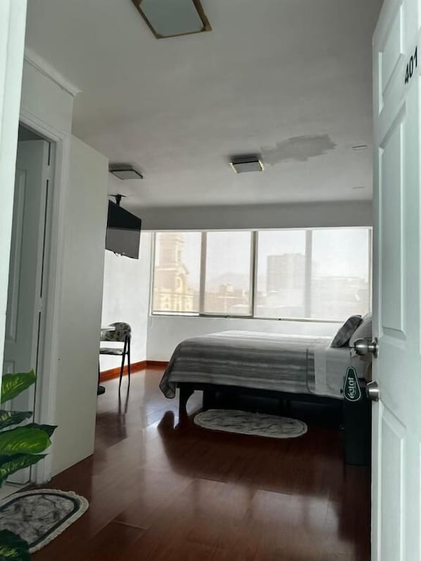 A bedroom with a bed, a chair, a window, and a door.