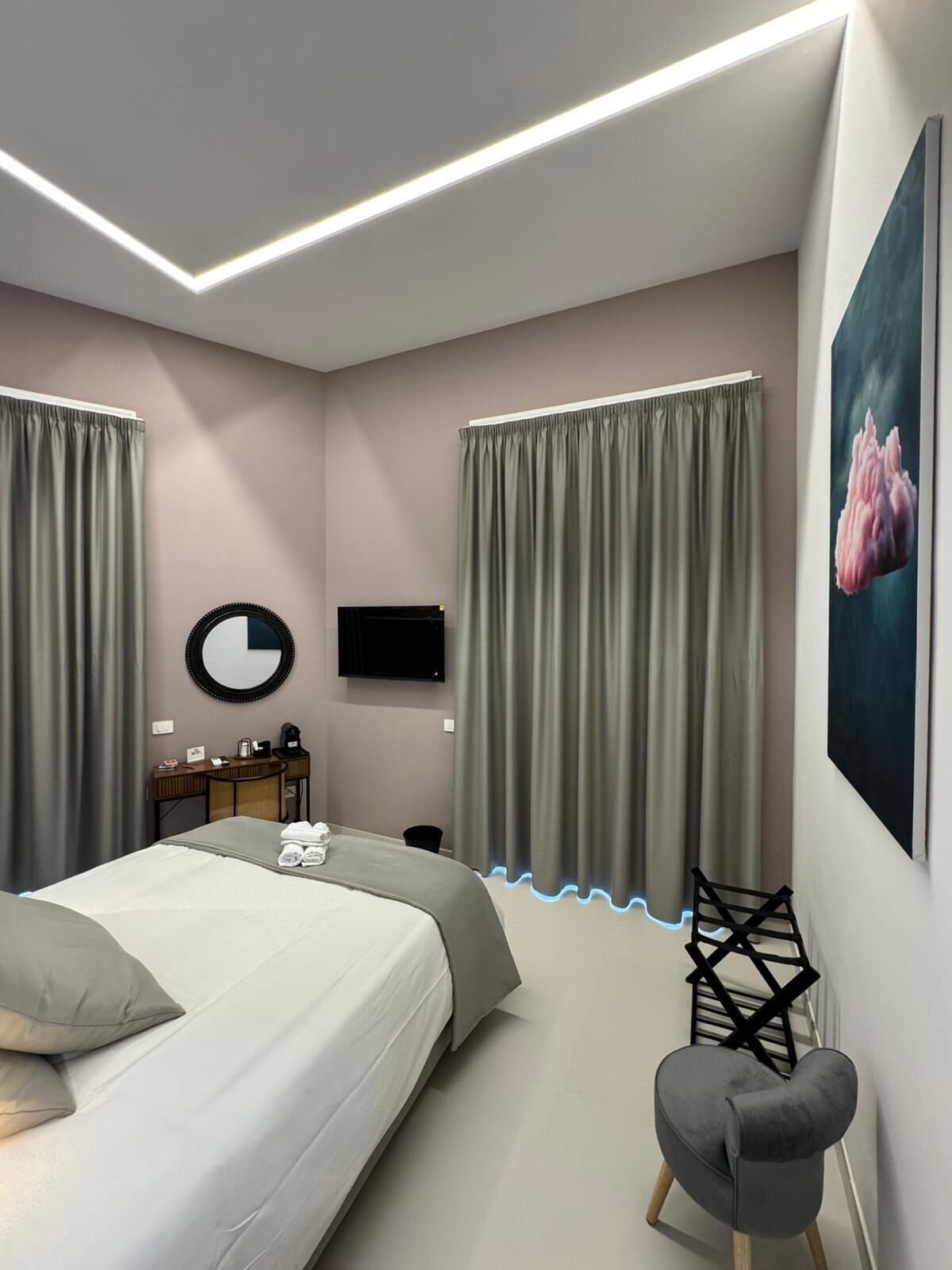 Quarto moderno com cama, escrivaninha, cadeira e televisão.