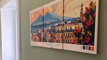 A wall with a colorful painting of Naples, Italy, featuring buildings, mountains, and a flag.