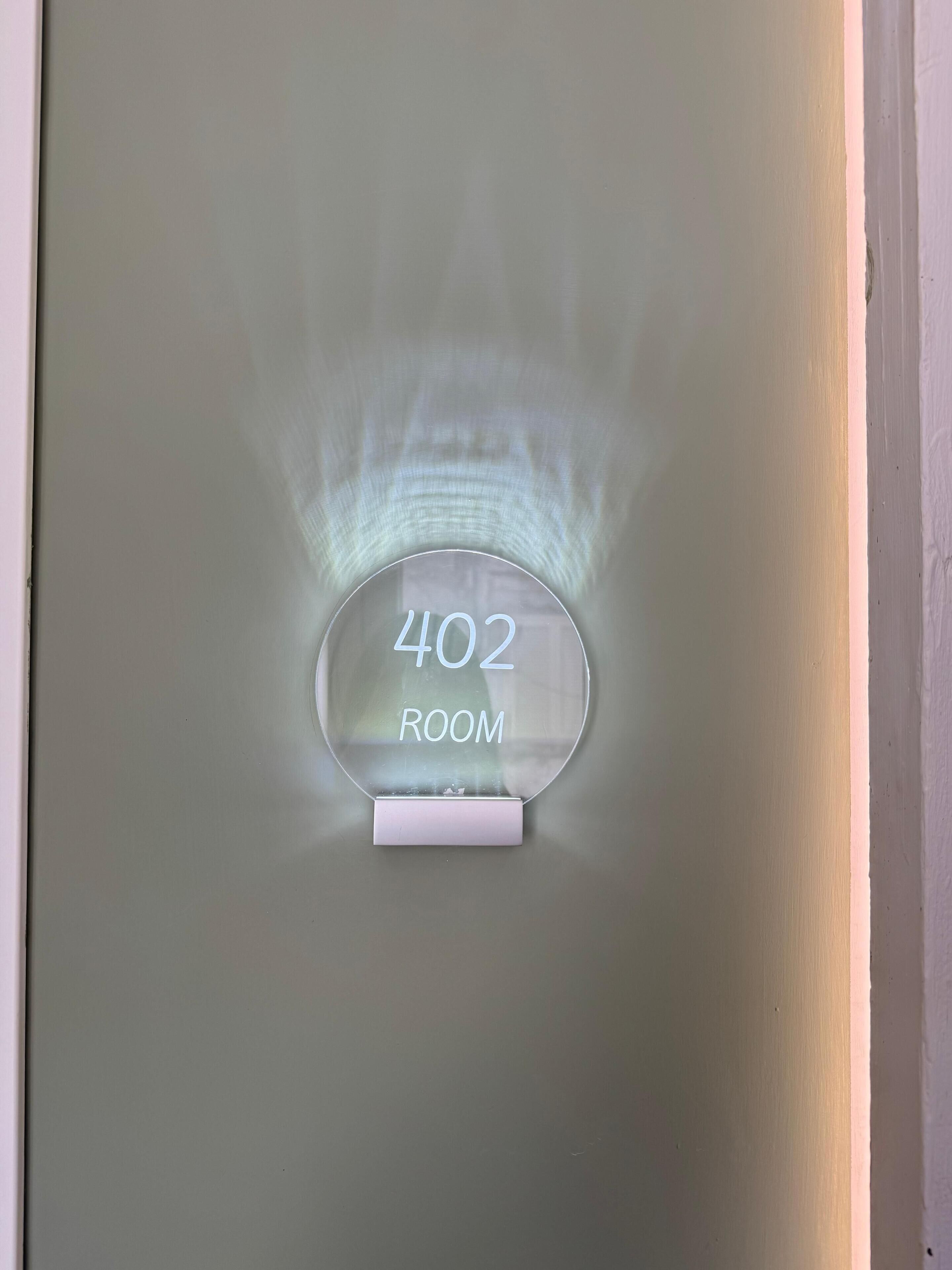 A clear glass sign with '402 ROOM' indicating a specific room number.