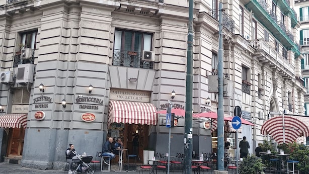 A historic building with multiple ground-floor shops, including a pastry shop and a cafe. - Poerio Station Rooms & Apartment  (Naples)