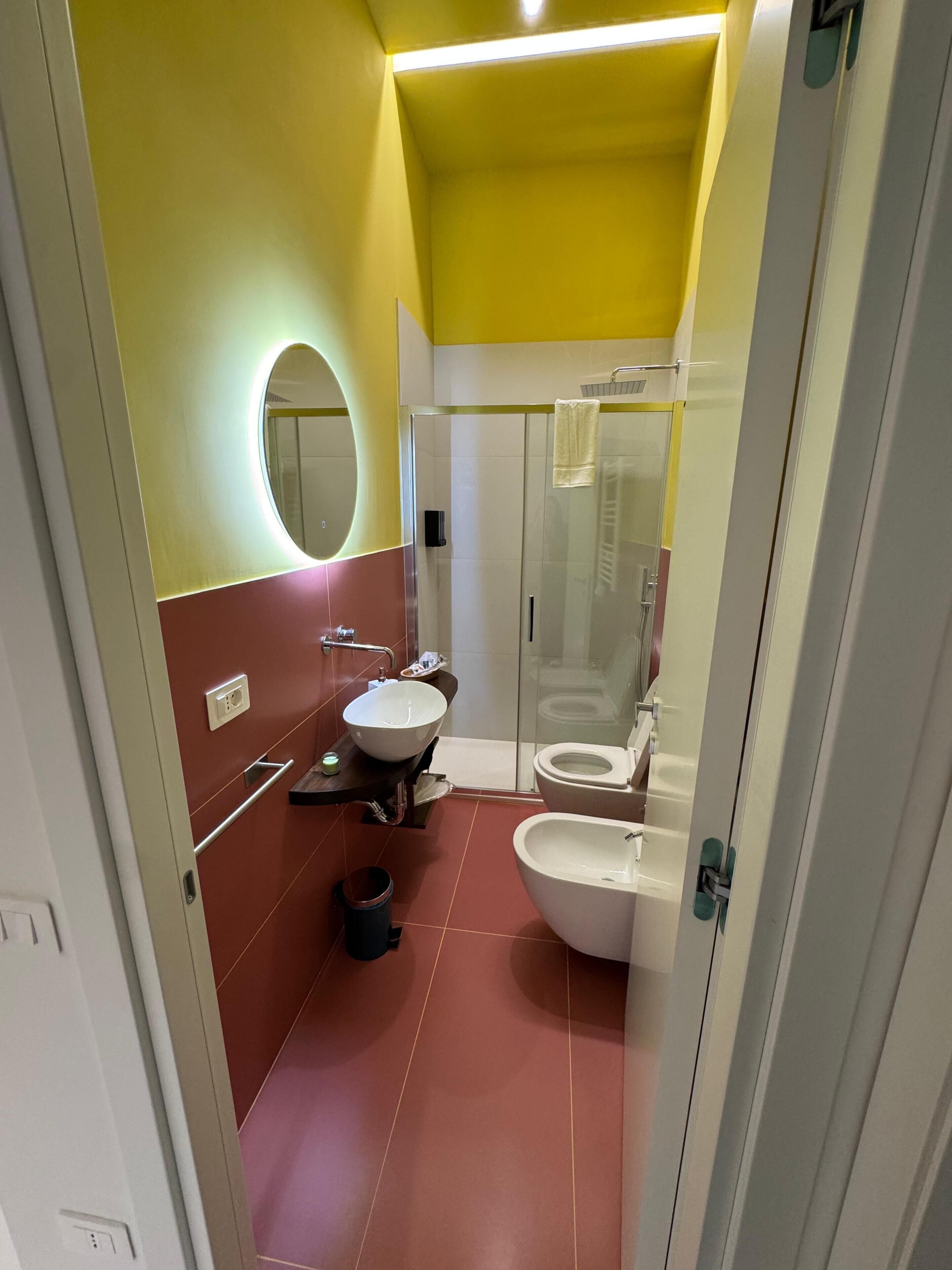 A bathroom with a glass shower enclosure, a white sink, and a toilet.