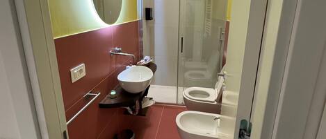 Un baño con cabina de ducha de vidrio, un lavabo blanco y un inodoro.