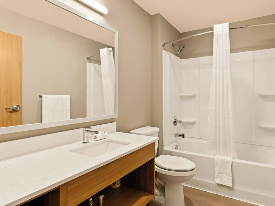 Ein modernes Badezimmer mit Waschbecken, Toilette und Badewanne in Weiß.